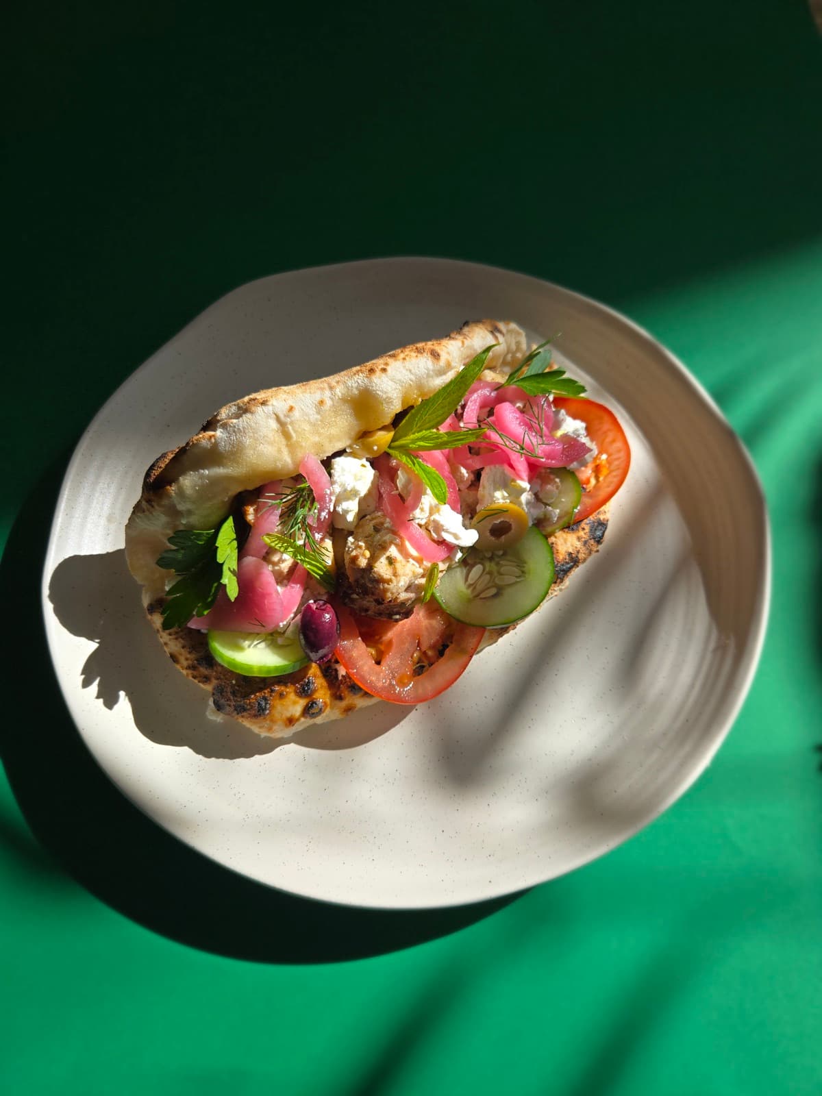 Hellenic Hype Ozzo with char-grilled chicken, top-down on a green background