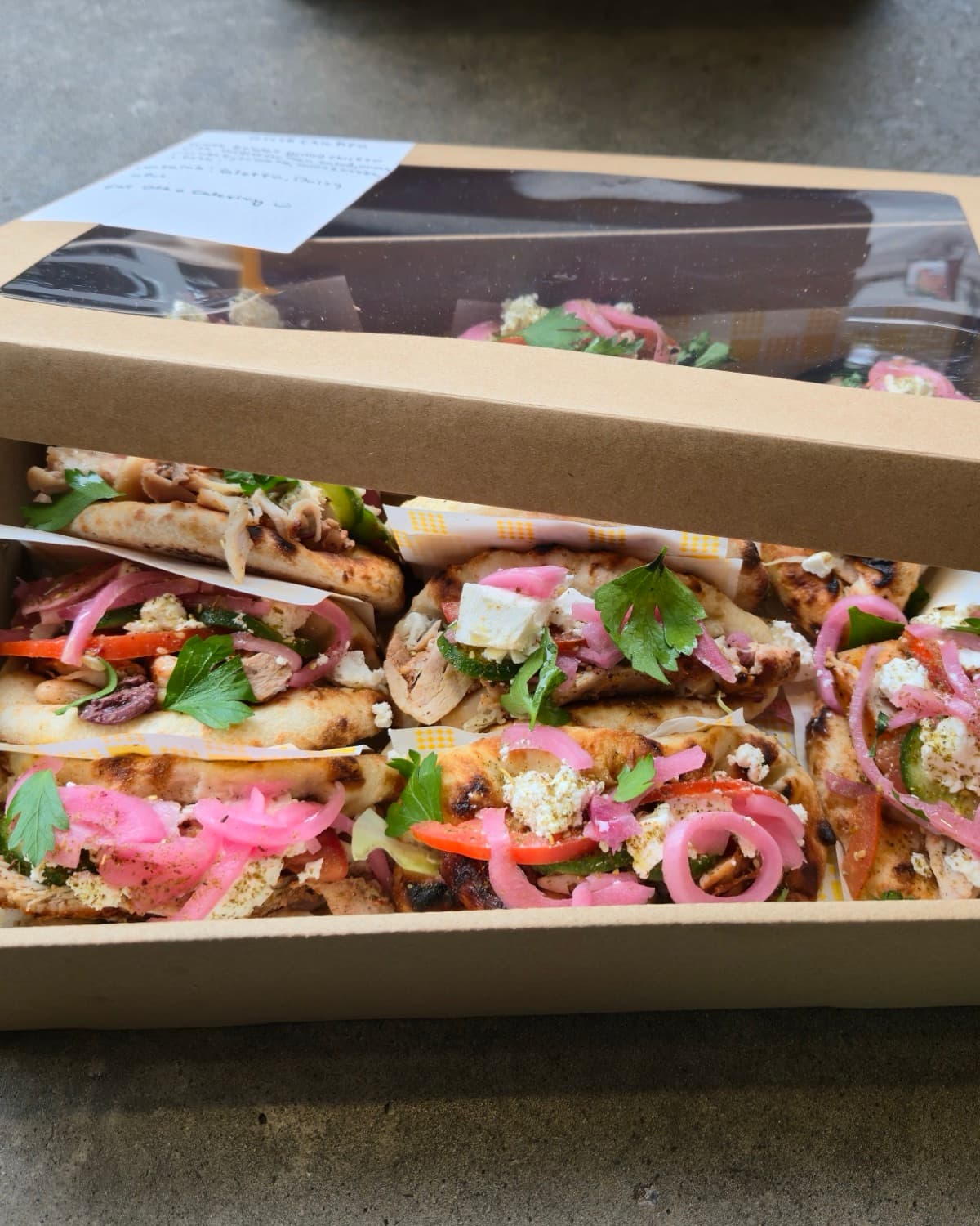 A generous Eat Ozzo catering box of wood-fired Ozzos with pickled onion and herbs, set out for a Sydney event