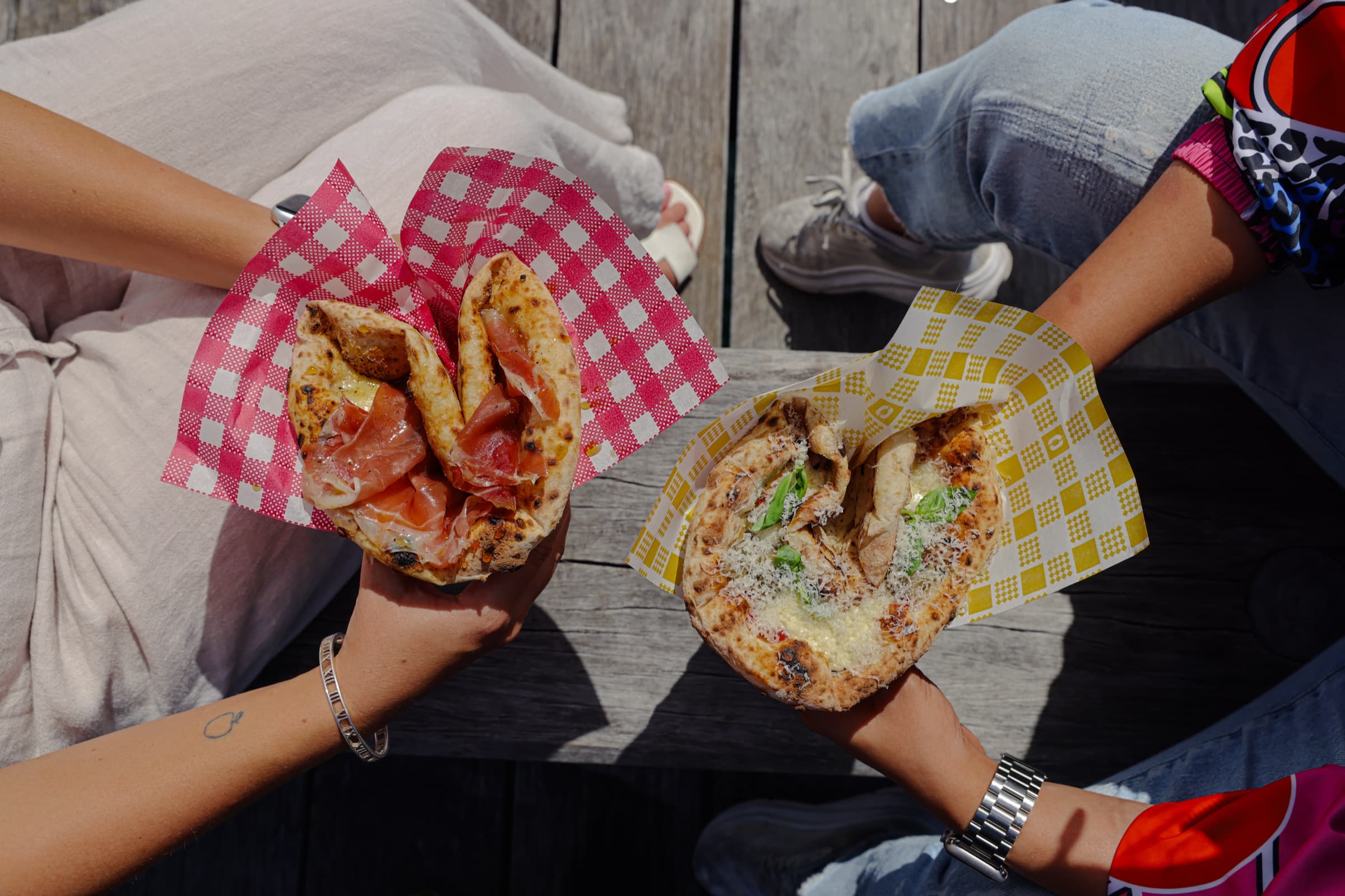 Two ozzos in checkered paper — prosciutto and a parmesan-pistachio combo — eaten on a Pyrmont bench