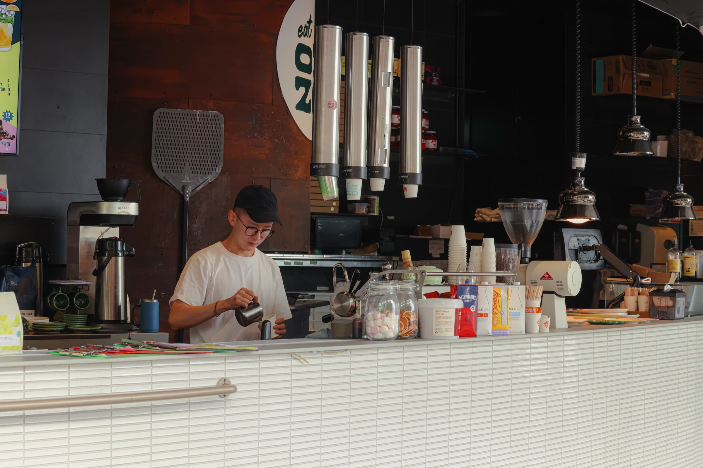 Eat Ozzo Pyrmont barista steaming milk at the counter under brand signage